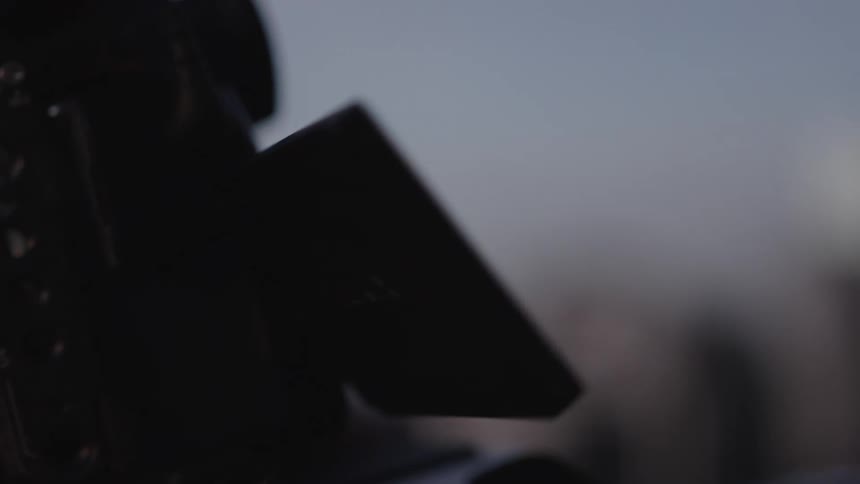 Male photographer reviews pictures on his camera while standing outdoors after dusk