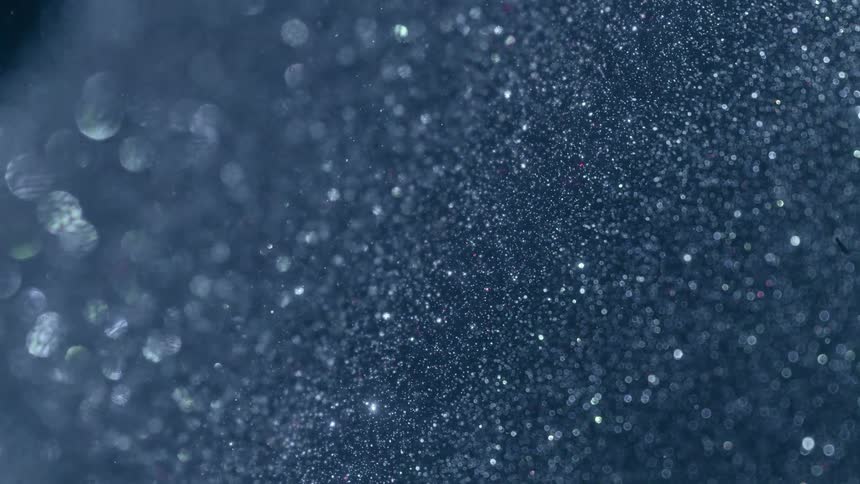 A closeup of a textured dark blue surface dotted with countless tiny outoffocus light reflections