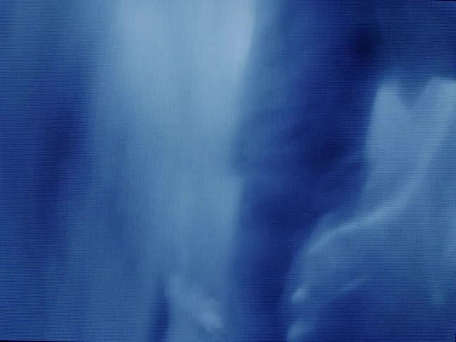 People stand silhouetted behind draped fabric in a dimly lit room