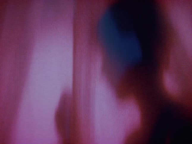 A woman is holding a flower behind the plastic