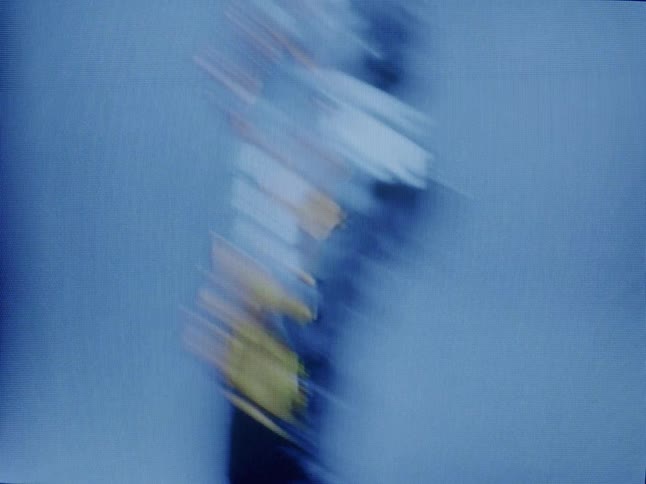 A young woman wearing a shiny jacket models against a blue background