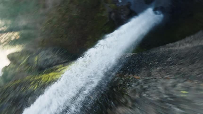 A fastmotion twisting shot captures water cascading over a rocky edge forming a tall waterfall