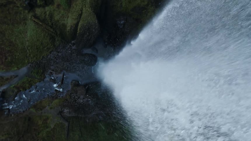 The camera is going towards a waterfall and it twists and turns as it is going through the water and the spray