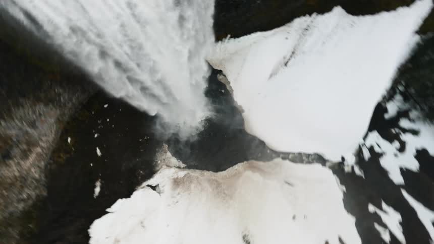 Aerial view of a snowy forest and a river falling free from a waterfall