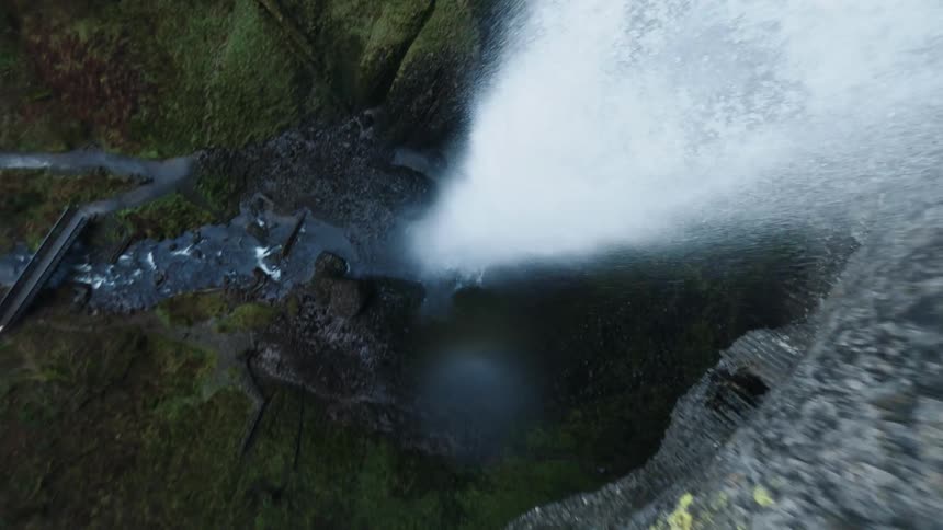 A waterfall cascades down a rocky cliff face creating a white rush of water and mist