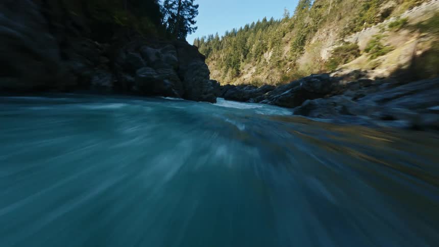 A river is flowing fast through the mountains and forest landscape