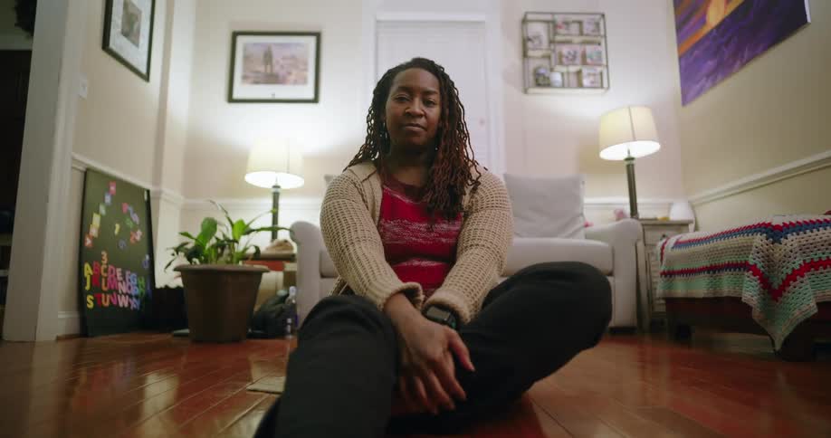 A woman is sitting on the wood floor