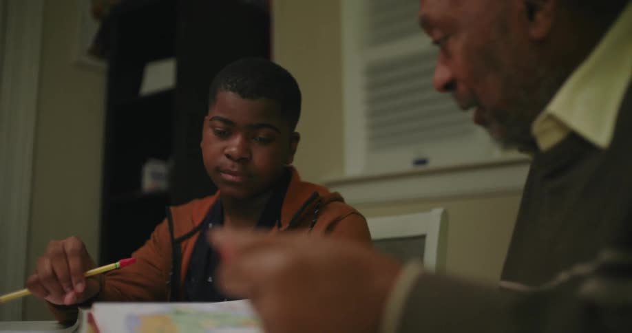 A grandfather is helping his grandson do homework