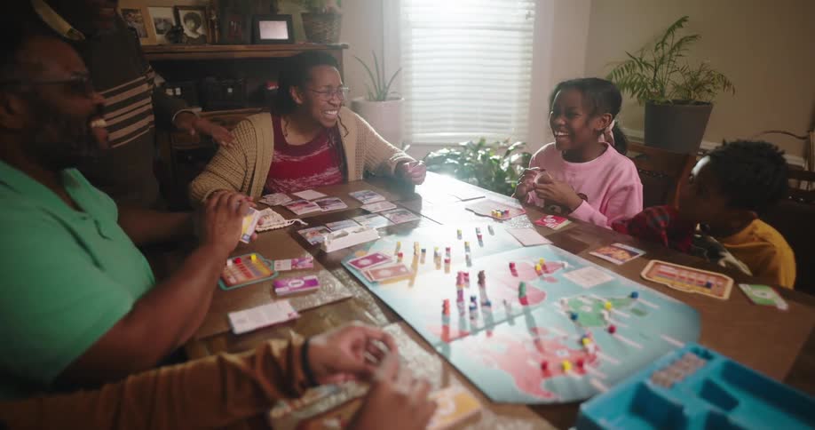 A family have fun gathered around a table playing a tabletop game