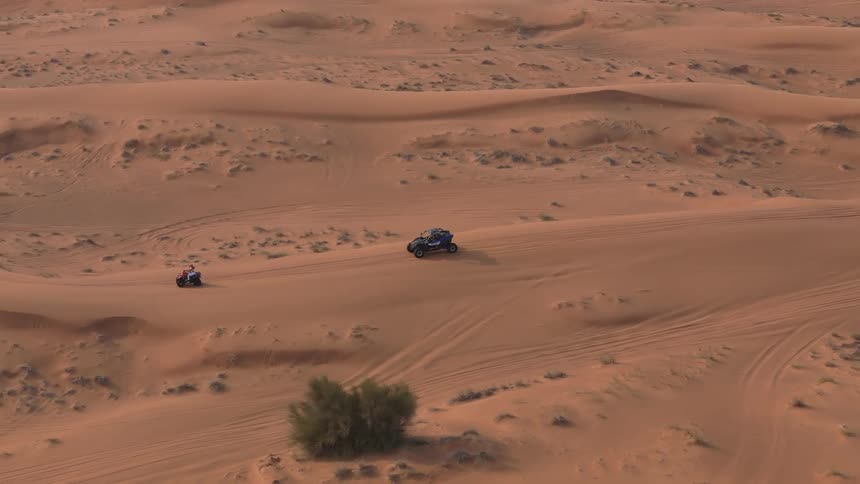 Recreational vehicles are driving across dunes in a desert