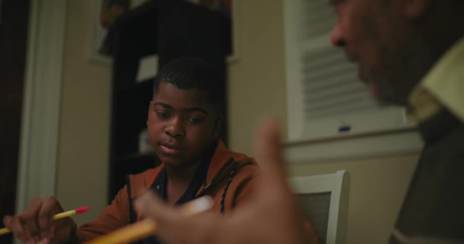 A man is tutoring a boy at home