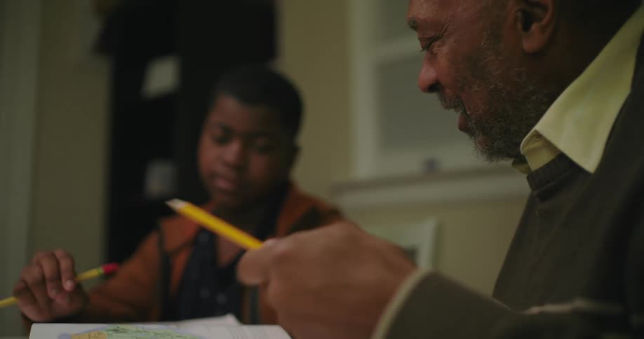 Father and son sitting on a table at home doing homework