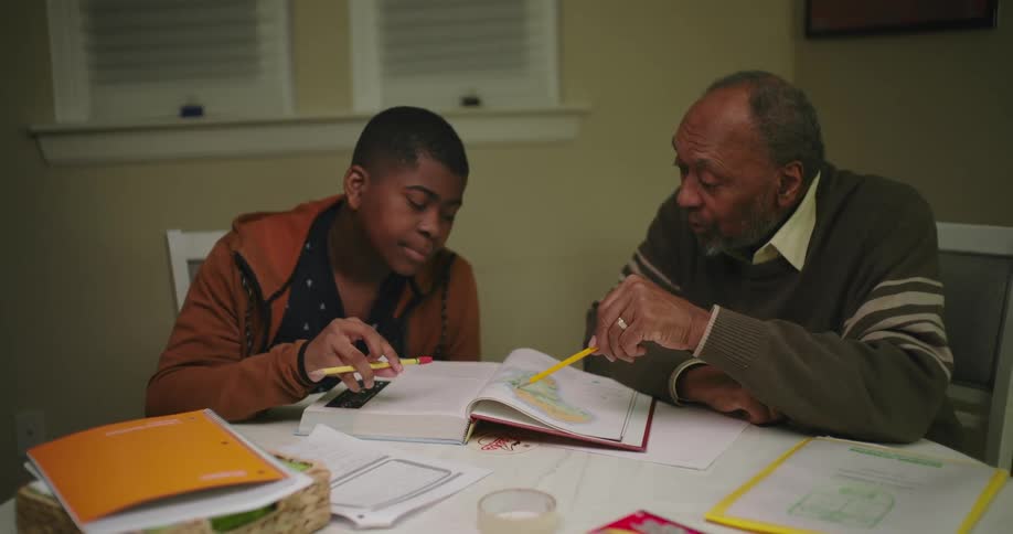 A grandfather is helping his grandson study