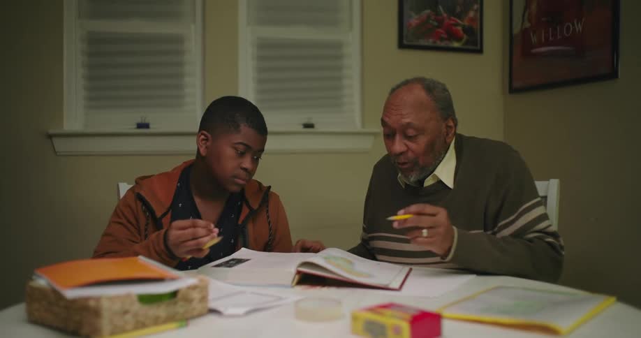 A man assists a young teen with their homework at home