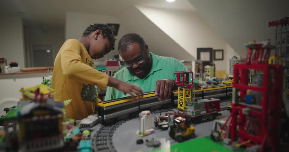Father and son have fun playing with a train model at home