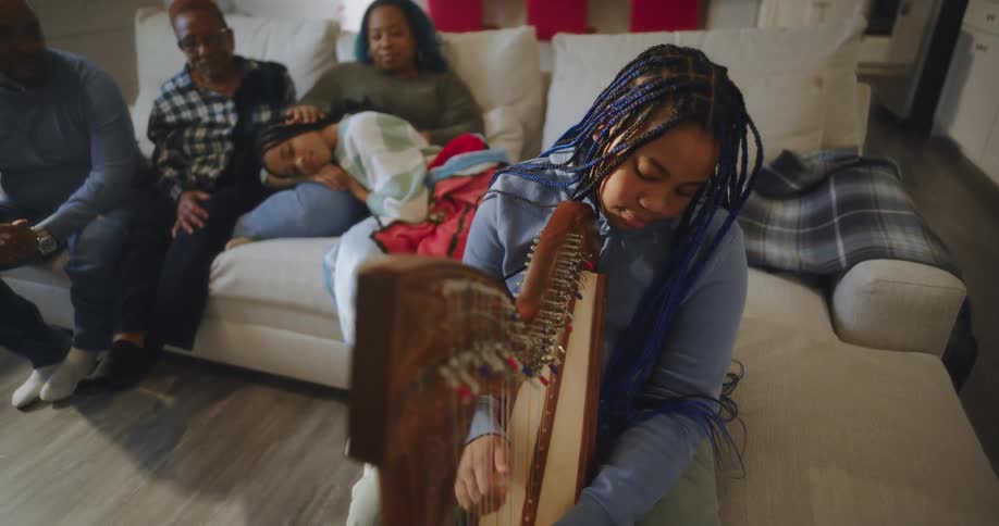 A family is listening to a girl play the harp