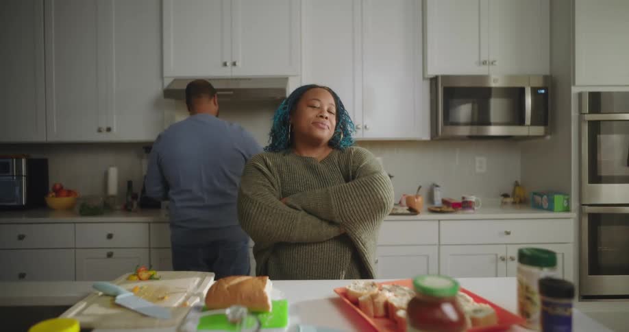 Man and woman cooking in the kitchen with woman crossing her arms