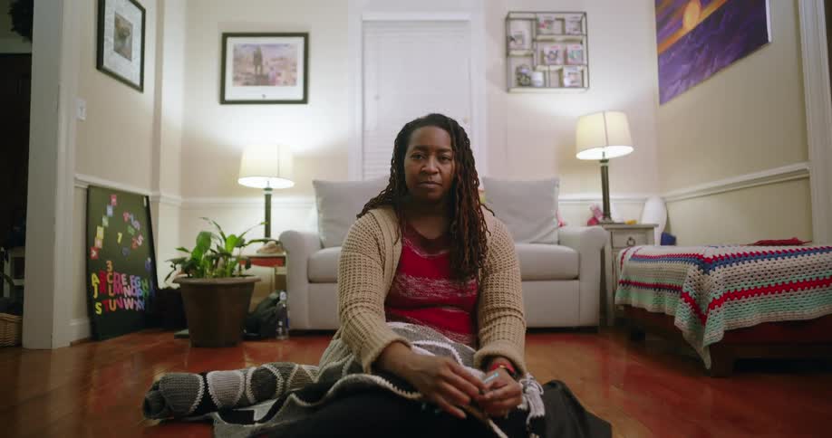 Woman sitting on the floor of a living room knitting