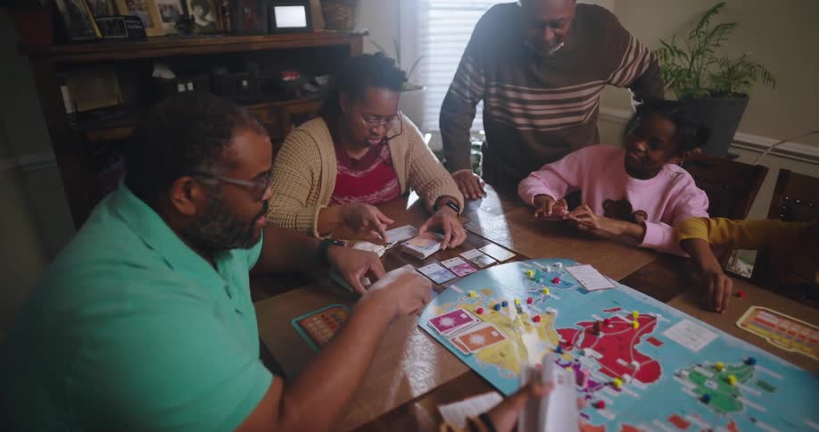 A family sits at a dining room table playing a game