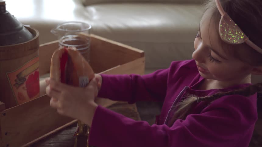 Girl kneeling in the living room plays with various items on the coffee table during the day