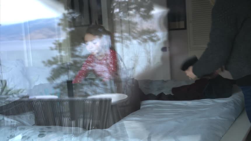 A little girl is excited as her mother folds clothes and puts them in a suitcase