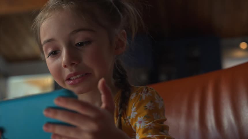 Close up of a girl playing with a smartphone while sitting on a couch in the living room