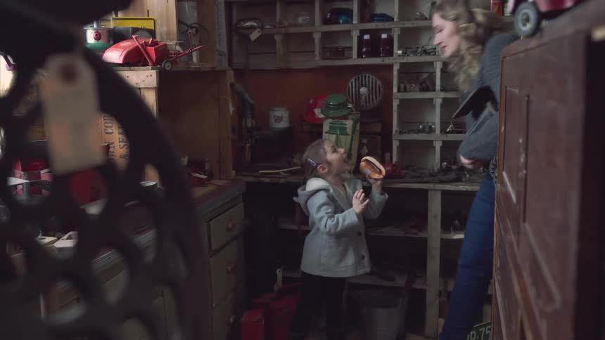 A girl and her mother in an antique shop listening to a seashell