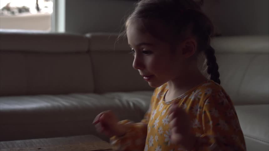 Little girl playing with marbles on a wooden table