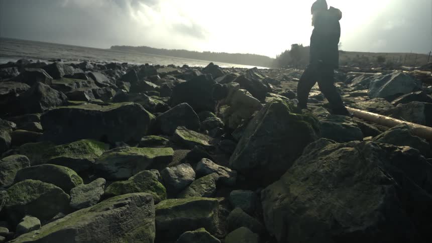 A woman follows a child climbing on the rocks
