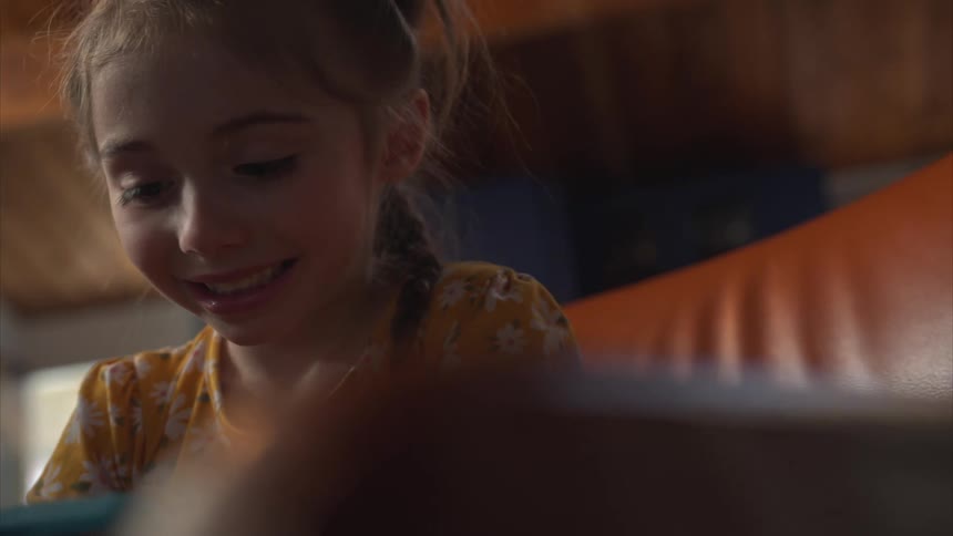 A little girl smiles as she plays on a tablet