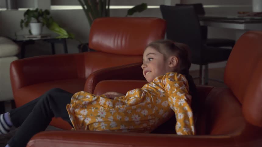 A girl is spinning and playing on the chair