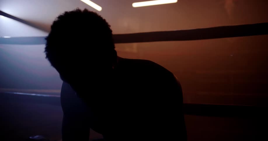 A man is resting on the side of a boxing ring