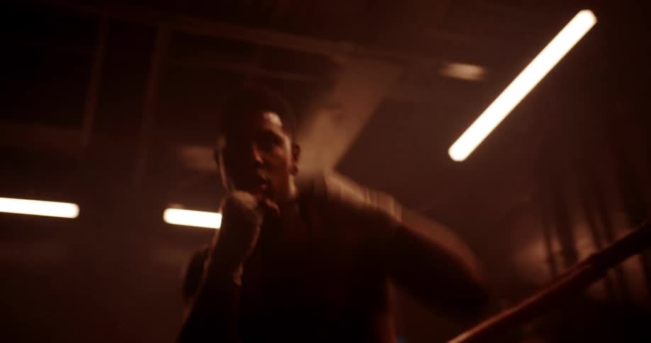 A man is shadowboxing in a dark room