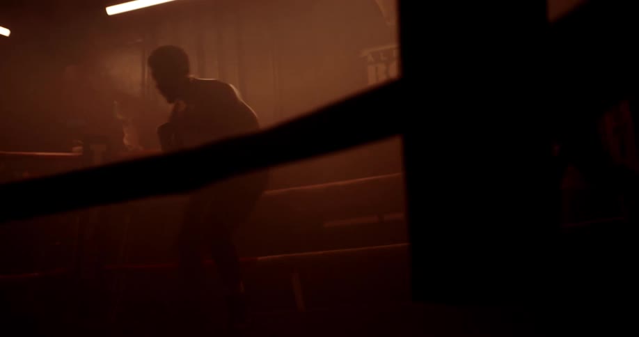 A man is shadowboxing in a boxing ring in a gym