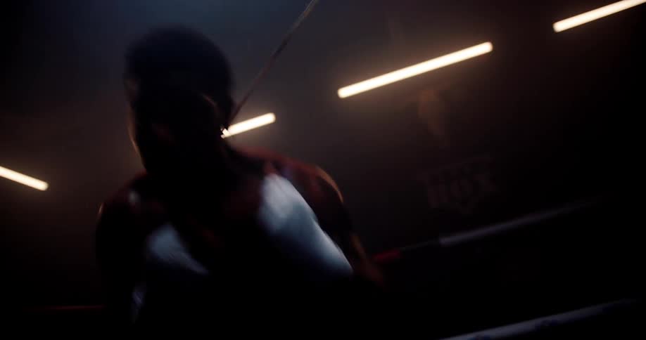 Male boxer sweats while training in the boxing ring with the aid of a cable