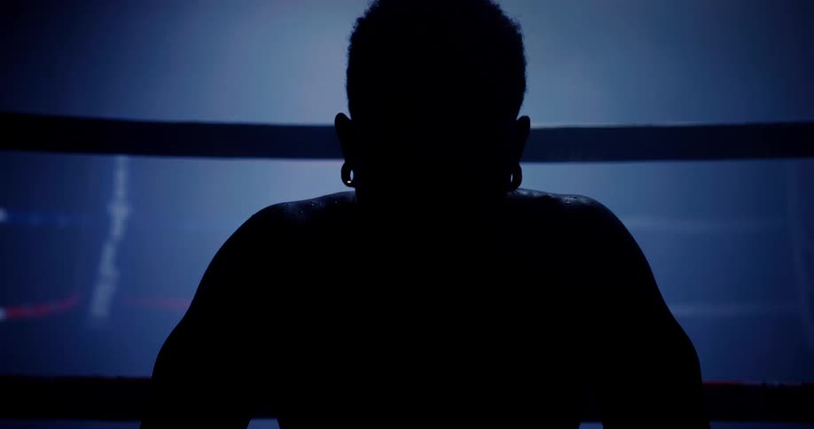 A man is sitting in the shade on the boxing ring
