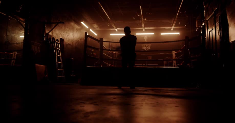Silhouette of a man jumping rope in a lowlight boxing environment