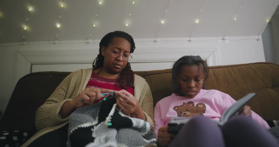 A mother is knitting while a girl reads