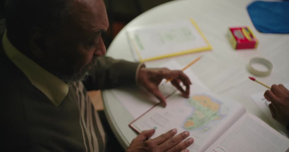 The grandfather is helping his grandson study
