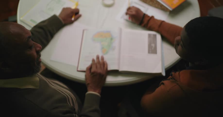 A teenager is getting tutored by his grandfather