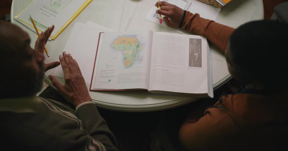 Father studying with son sitting at a table with an open book