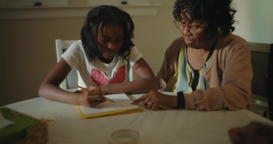 Mother and daughter sitting on a table at home doing homework