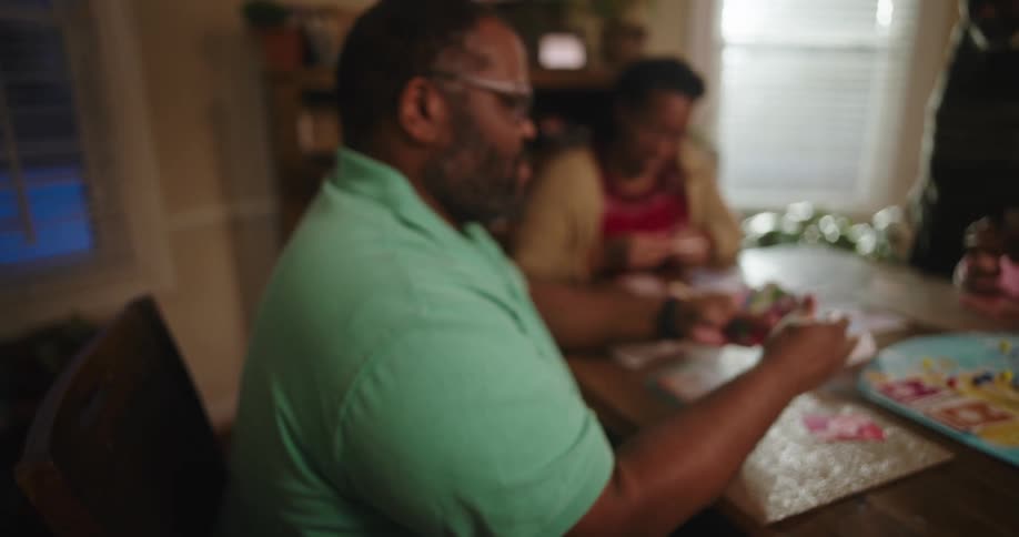 Family gathered around a table playing cards and board games