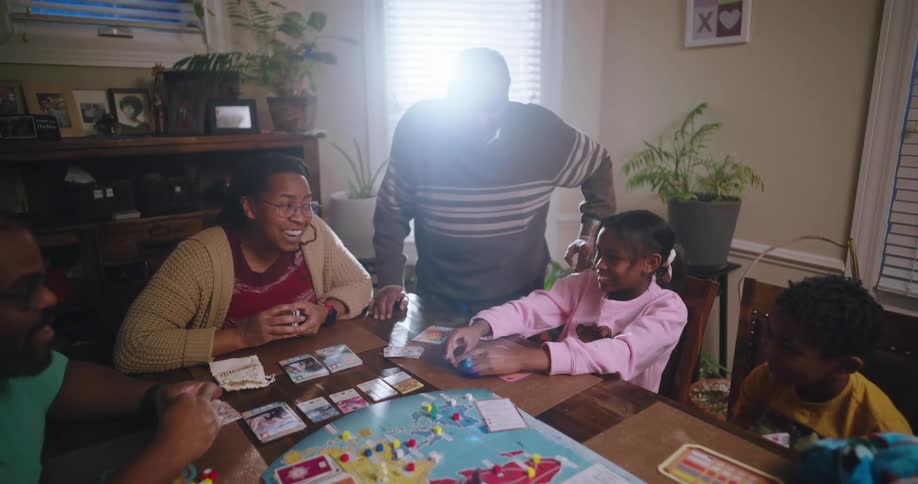 A family gathered around a table playing a board game with a large map and cards