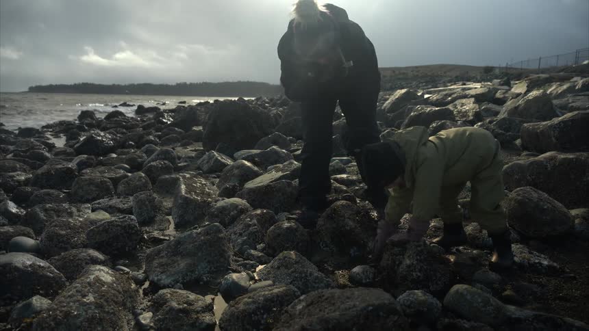 Mother and daughter among rocks on the seashore