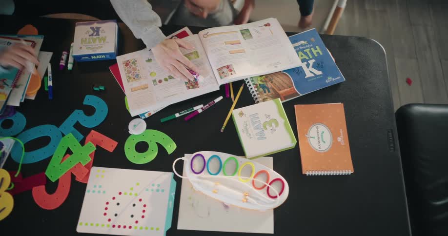 People are cleaning up papers and markers on a table