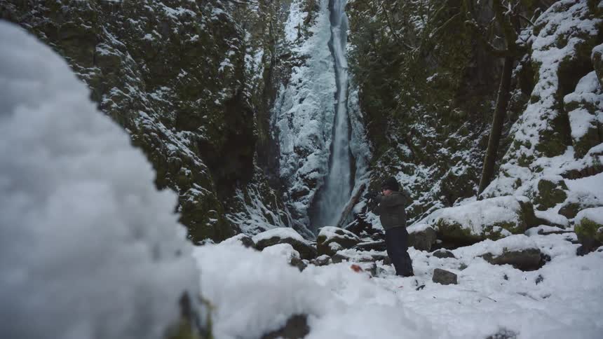 Girl in the middle of the snow next to a waterfall
