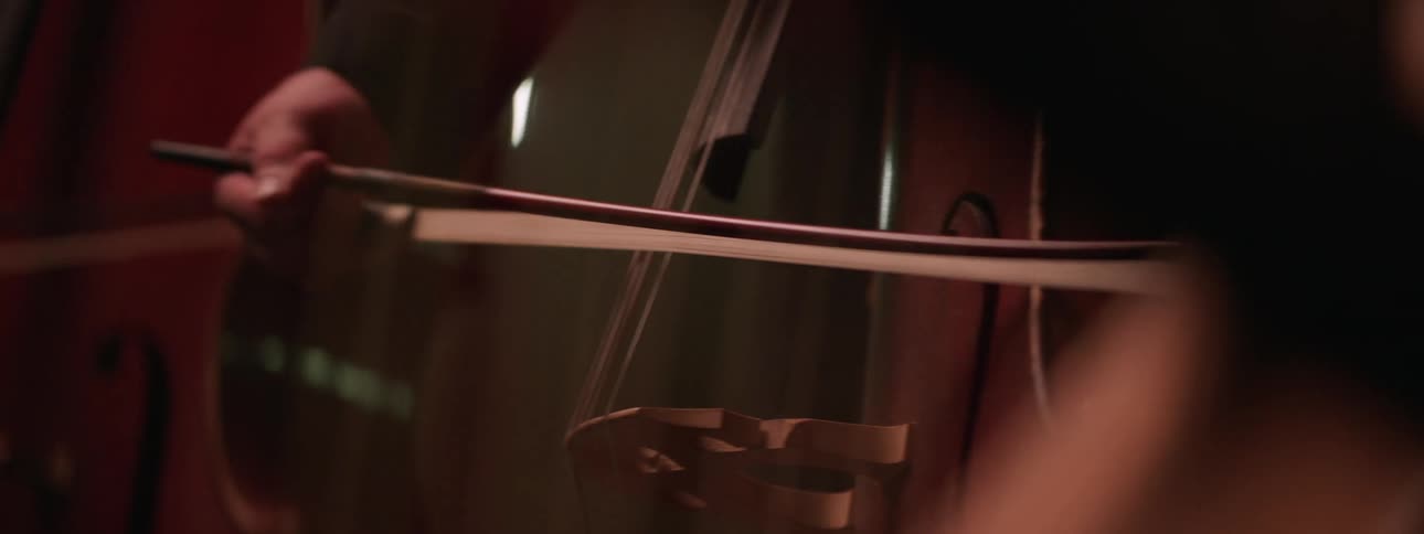 A hand holding a bow and playing a string instrument