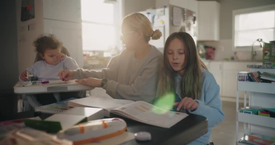 A mother helping her daughter with homework in the kitchen at home