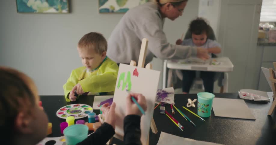 A family is painting at the dining room table